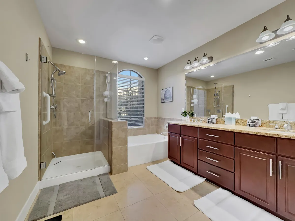 A spacious, modern bathroom with a double sink vanity, large mirror, walk-in shower, and standalone bathtub. Ample lighting and clean lines convey a sense of luxury and tranquility.