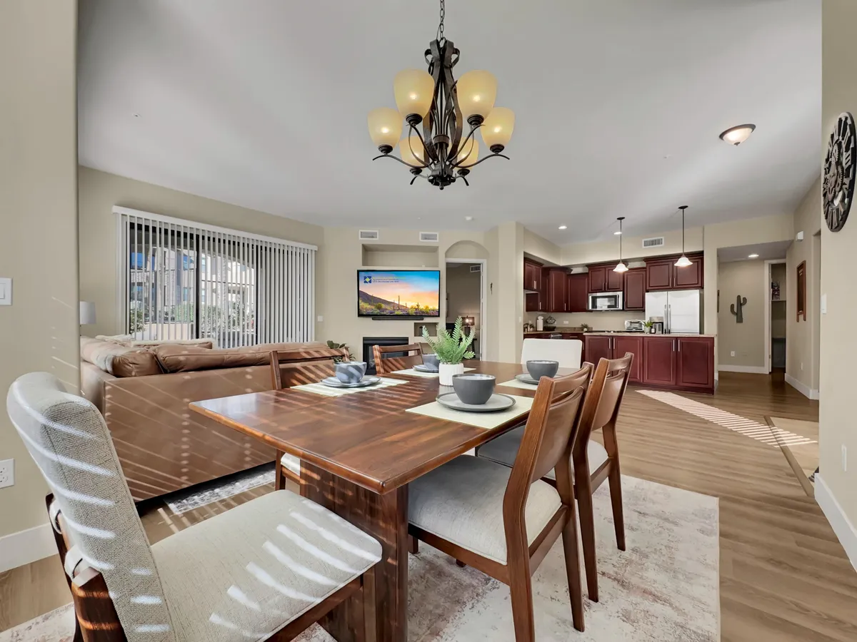 A welcoming dining area accented by a stylish chandelier, comfortable dining table, adjacent sofa, and visible modern kitchen appliances. The setting is ideal for family meals, entertaining guests, and casual gatherings, radiating warmth and togetherness.