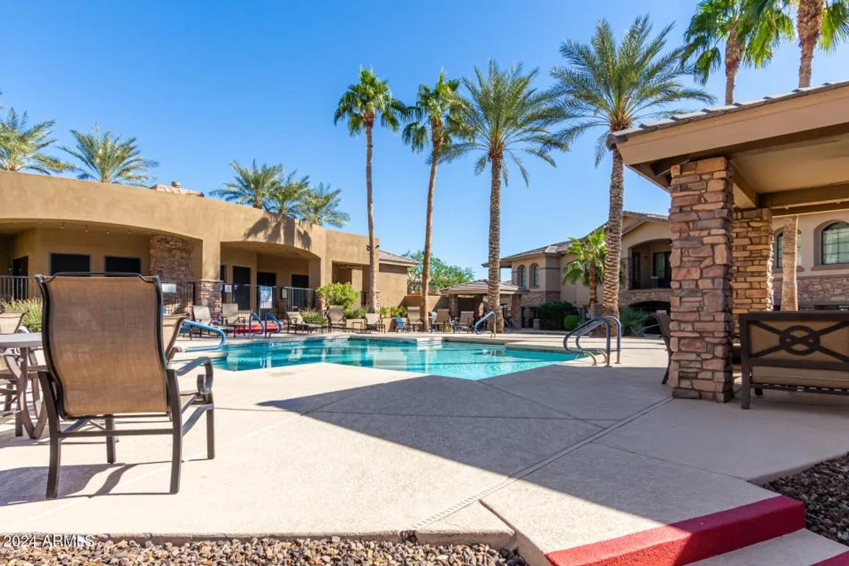 A tranquil swimming pool surrounded by palm trees and modern building architecture, with lounge chairs set up for relaxation and socializing after a day spent exploring outdoors.