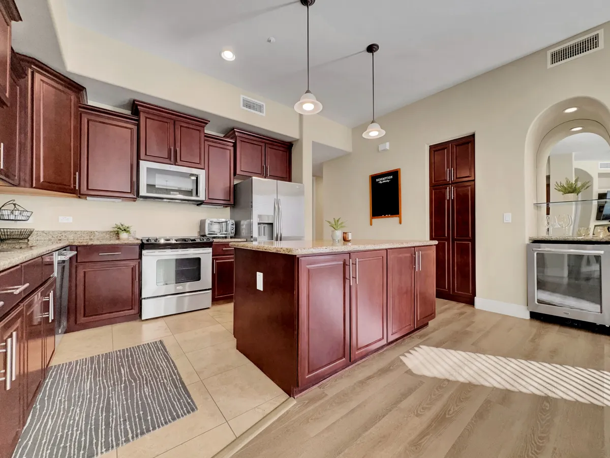 A modern kitchen with dark wood cabinetry, a central island, stainless steel appliances, and granite countertops. The kitchen appears ready for meal preparation and social gatherings, offering generous counter space and high-end finishes.