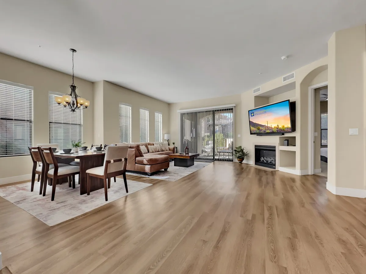 A cozy, inviting interior with a dining table, sofa, television, and sliding glass door leading outside. The space feels connected to the outdoors and perfect for gathering with friends or family.