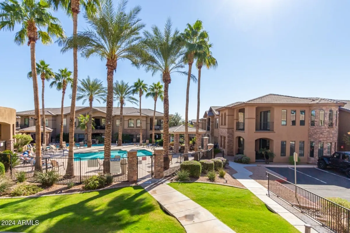 This image showcases a serene outdoor swimming pool surrounded by palm trees, modern buildings, and a landscaped lawn. The inviting lounge areas and sparkling water provide a resort-like ambiance ideal for unwinding after a workday or socializing outdoors.